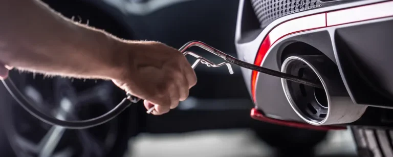 Emissions test probe in car exhaust during inspection