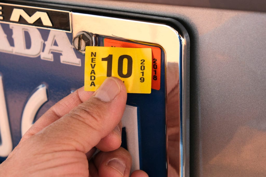 placing an updated registration sticker on a license plate 