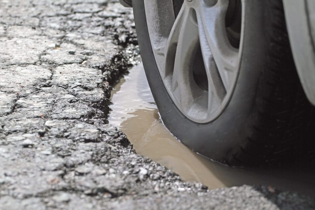 car tire in a pothole filled with water