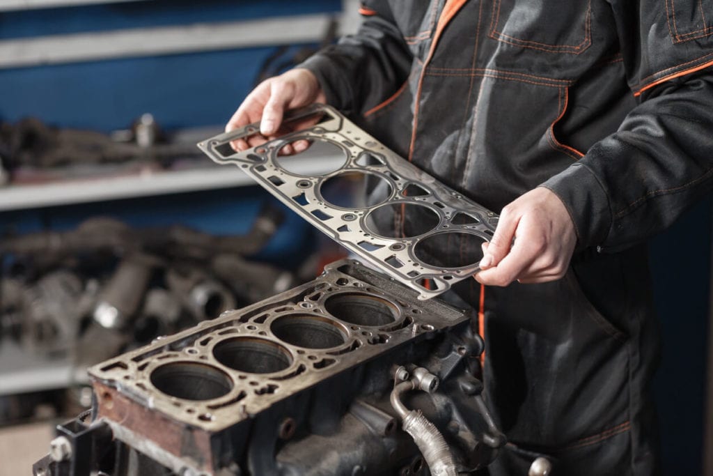 service technician holding engine head gasket