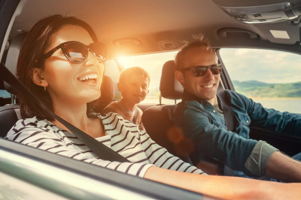 a couple sitting in the front seats of a car while driving