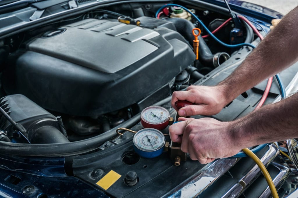 Man attaching cables to recharge car with Freon