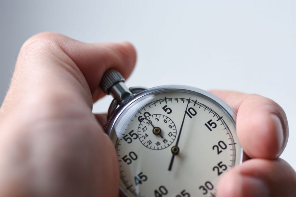 close up of a stopwatch with a thumb on the start button