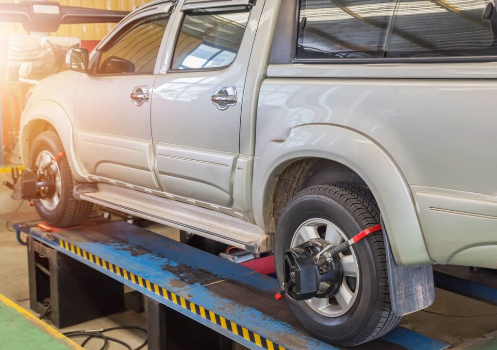 gray pickup truck getting wheel alignment service at service center