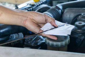 technician hands holding an engine oil dipstick