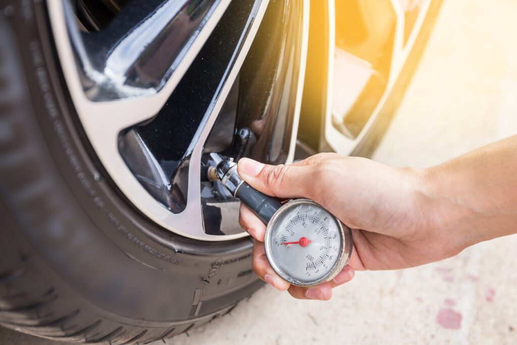 hand holding pressure gauge for car tire pressure