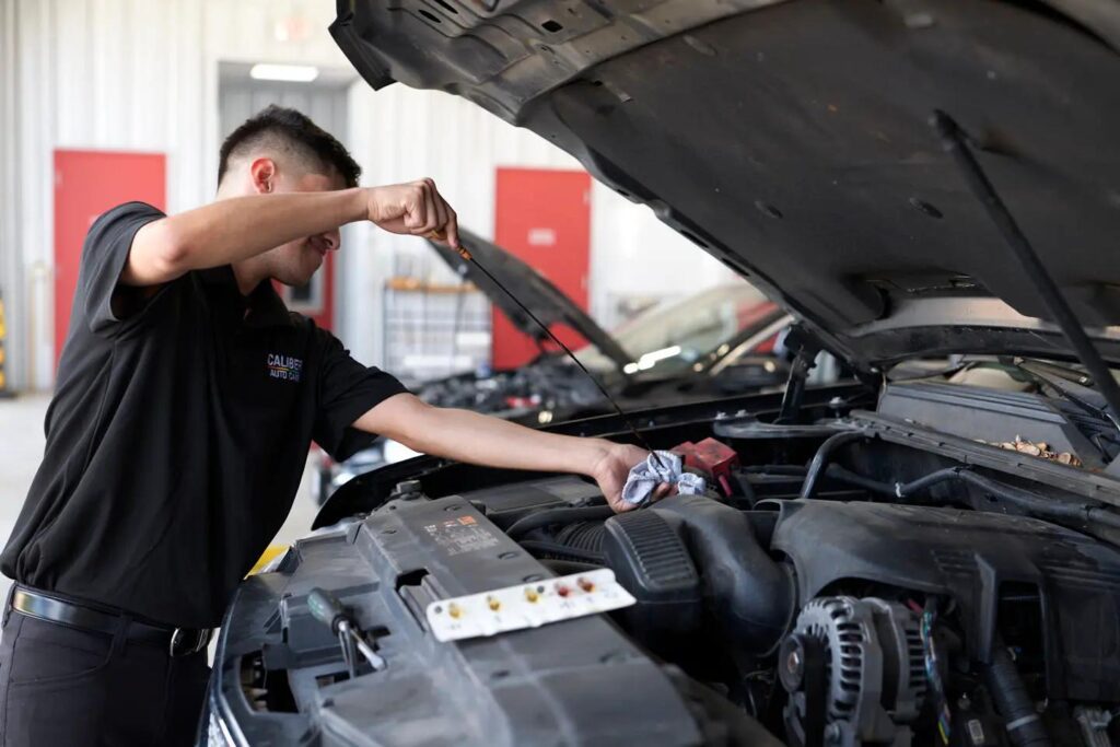 Auto technician checking engine oil